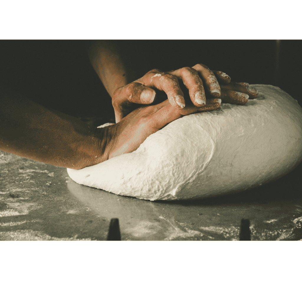 Mains pétrissant une Pâte à pizza professionnelle sur un plan de travail fariné, symbole de l'utilisation de farine pour pizza artisanale