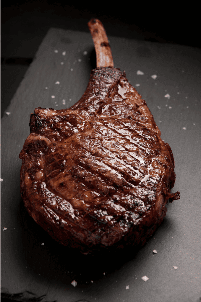 cote de boeuf sortant de cuisson d'un four a pizza poser sur une ardoise 