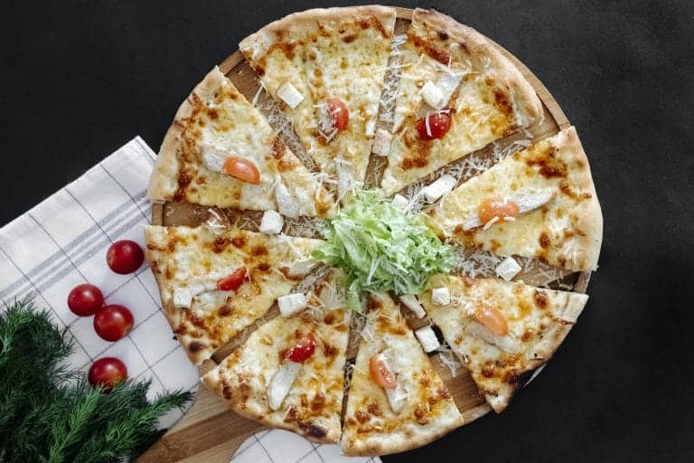 pizza chèvre miel découper en part posé sur une planche en bois