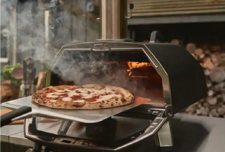 four a pizza karu 2 pro avec pizza bien chaude et fumer qui ce dégage qui sort du four a l'aide d'une pelle a pizza