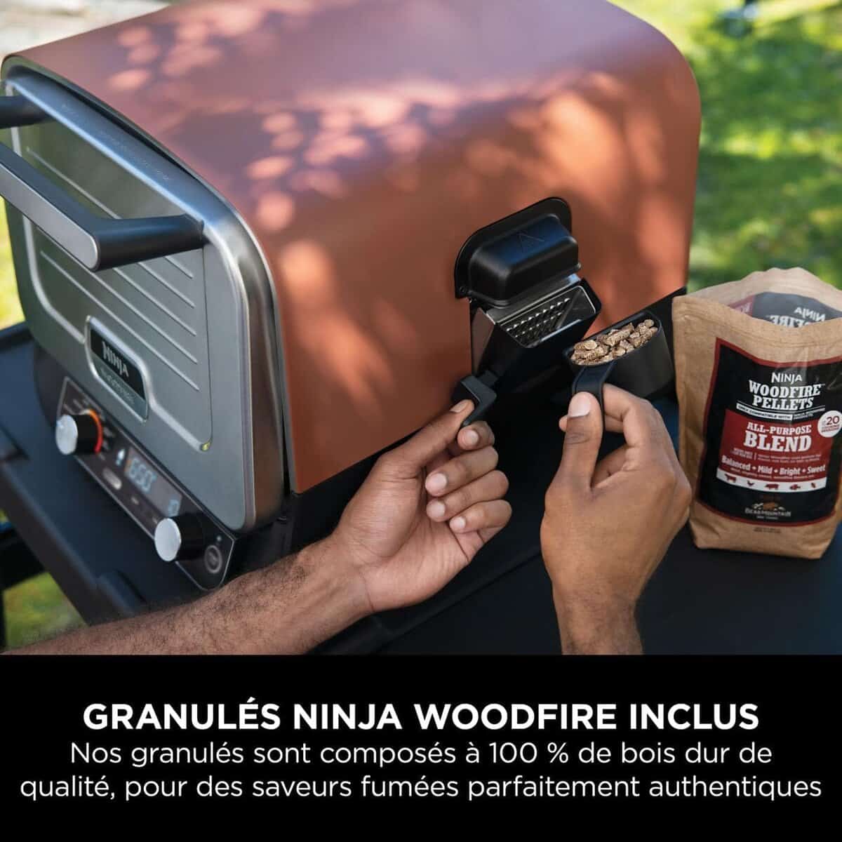 Ninja Woodfire OO101EU – Four à pizza extérieur électrique 8-en-1 (30 cm) 2 Gros plan sur l’insertion des granulés de bois dans le compartiment latéral du four.