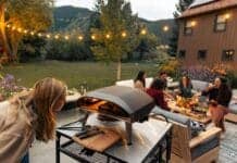 Ambiance chaleureuse de soirée en extérieur avec un groupe d’amis partageant des pizzas préparées dans le four Ooni Koda 16.