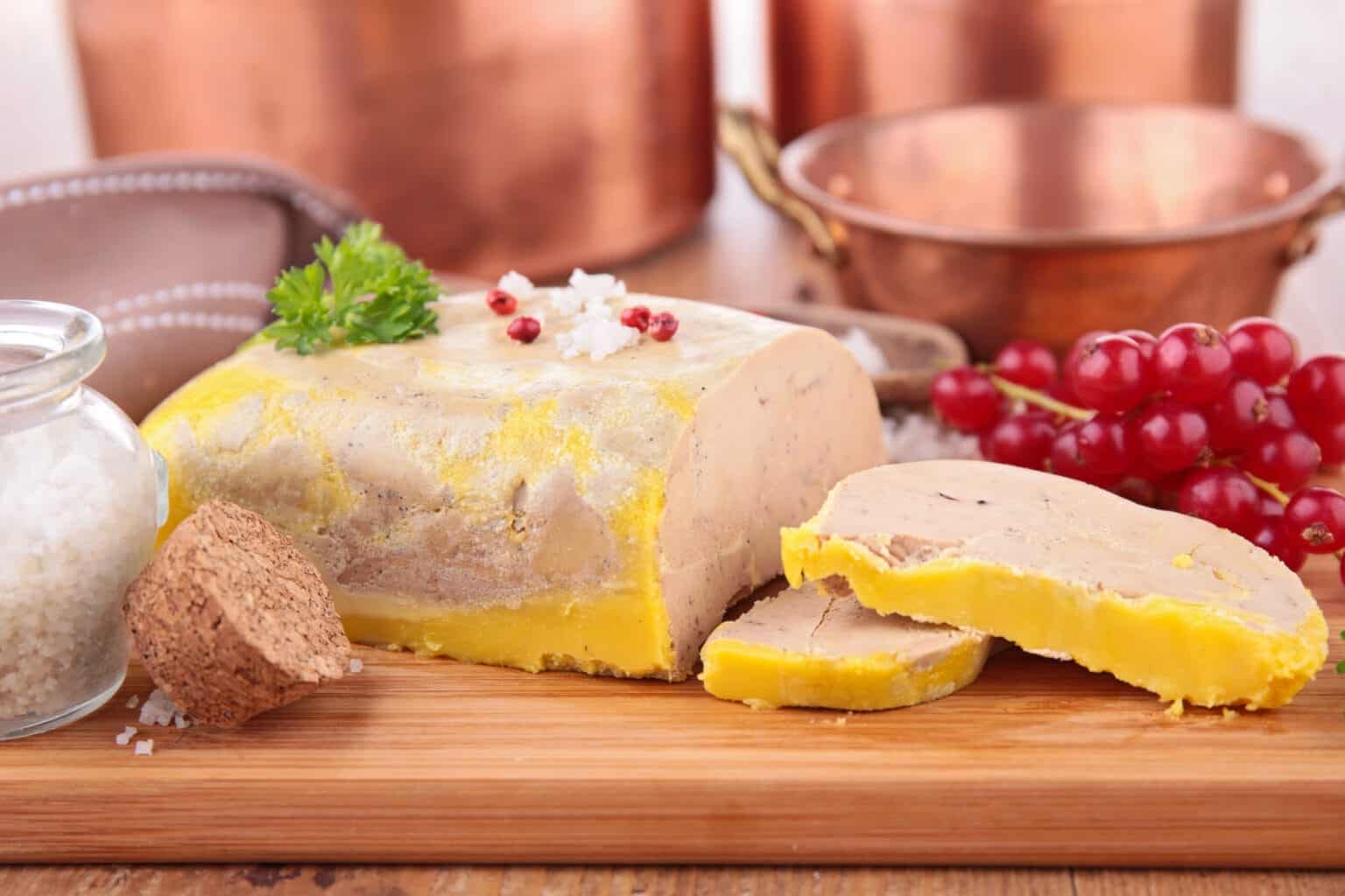 Foie gras cru fait maison présenté sur planche en bois, entouré de sel et d’aromates, parfait pour une cuisson foie gras traditionnelle ou moderne.