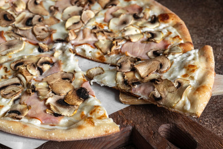 Pizza jambon champignons sur pâte fine avec mozzarella dorée, servie sur planche