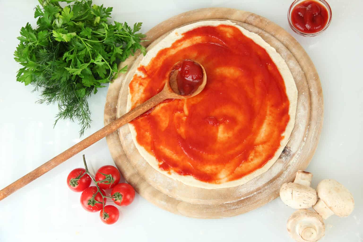 Sauce tomate pizza : secrets d'une sauce réussie 6 Pâte garnie de sauce tomate à pizza étalée à la cuillère avec herbes et tomates autour