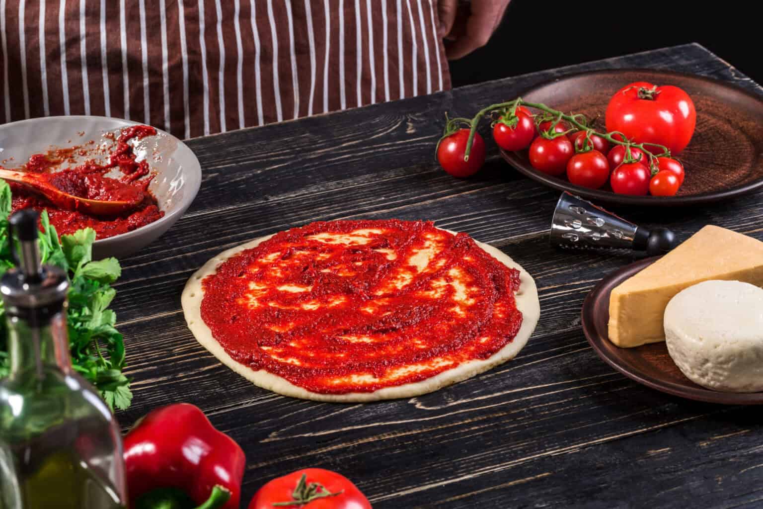 Sauce tomate pizza : secrets d'une sauce réussie 8 Sauce tomate pizza étalée généreusement sur une pâte crue avec tomates fraîches en décor