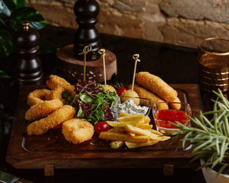 Mélange de friture italienne légère avec calamars croustillants, crevettes et poisson blanc servis avec salade fraîche et sauces.