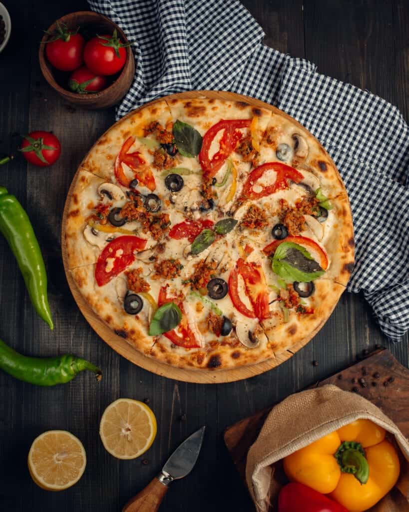 pizza orientale aux tomates, poivrons, olives noires et herbes fraîches sur pâte fine dorée
