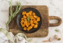 Cubes de butternut dorés et assaisonnés aux herbes de Provence dans une poêle noire, texture croustillante et fondante
