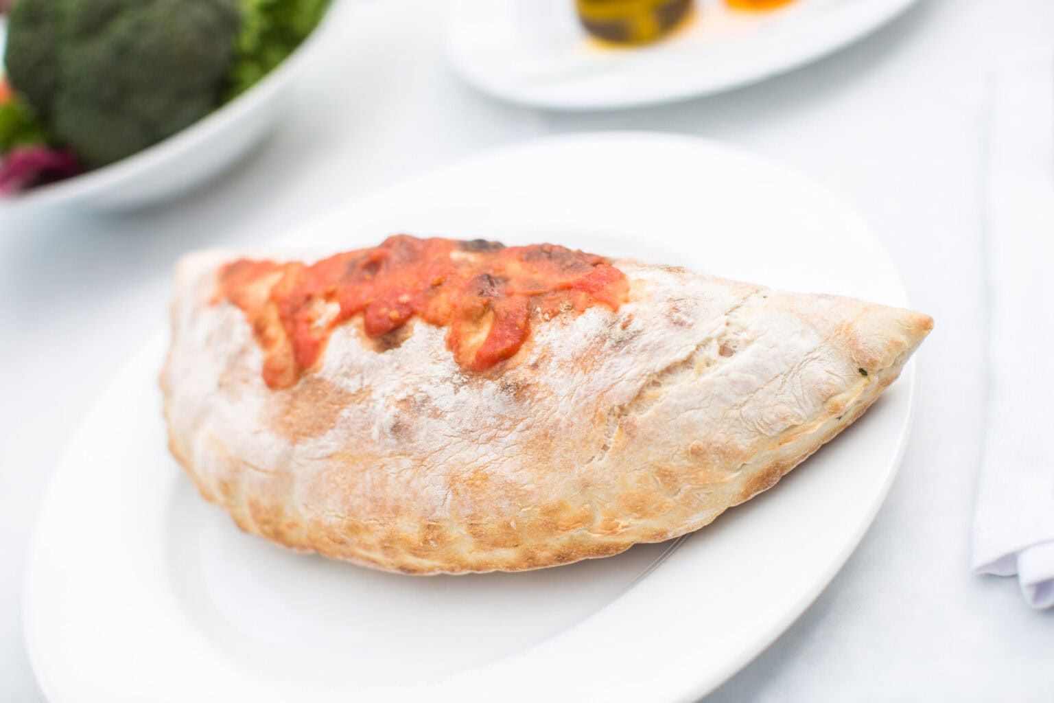 Panzerotti italien cuit au four avec garniture tomate-fromage sur assiette blanche