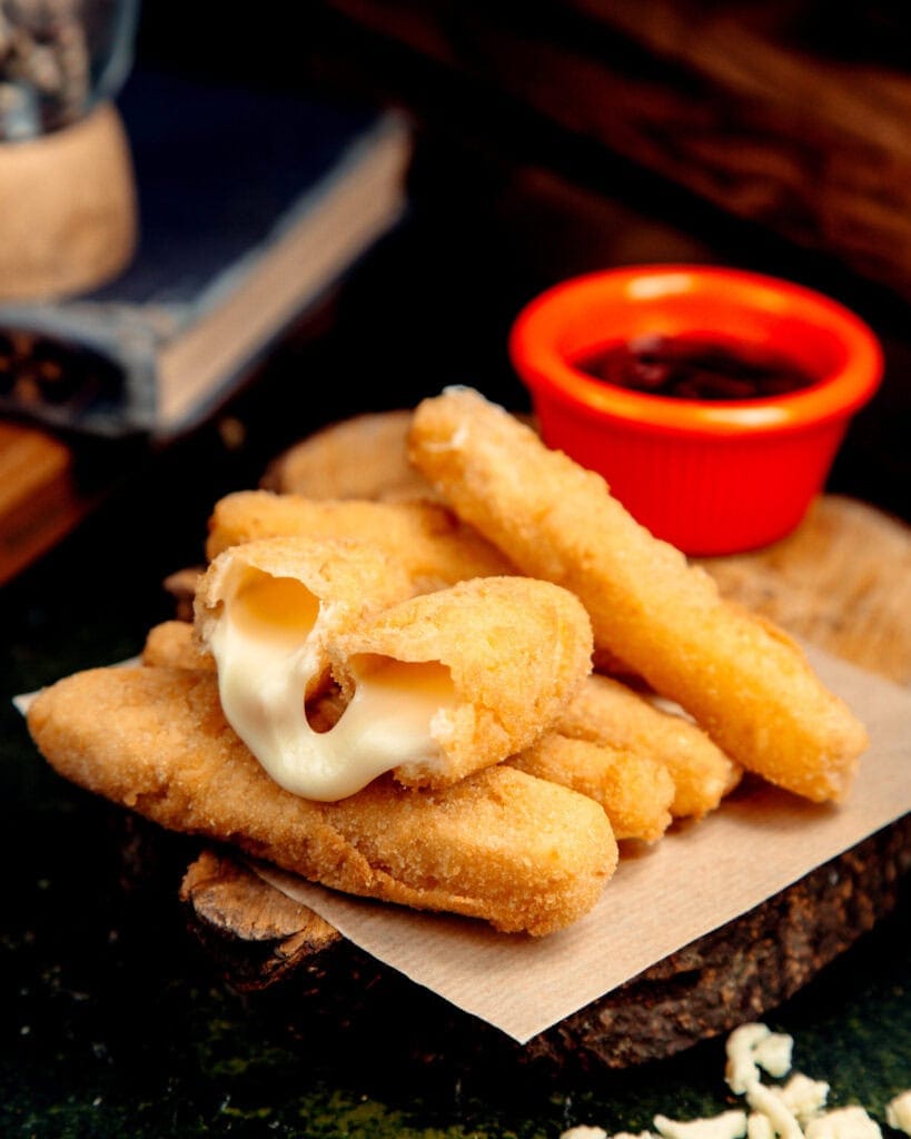 Mozzarella sticks Air Fryer : croustillants à l’extérieur, fondants à l’intérieur 10 Sticks de mozzarella panés prêts à cuire à l’Air Fryer sur planche en bois