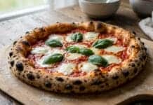 Gros plan sur une pizza Margherita fraîchement sortie du four, avec sa croûte croustillante, de la mozzarella fondue et du basilic frais sur une pelle en bois.